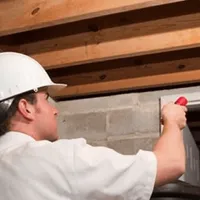 Termite inspection technician checking a basement wall and framing for termite activity in Pittsburgh, PA